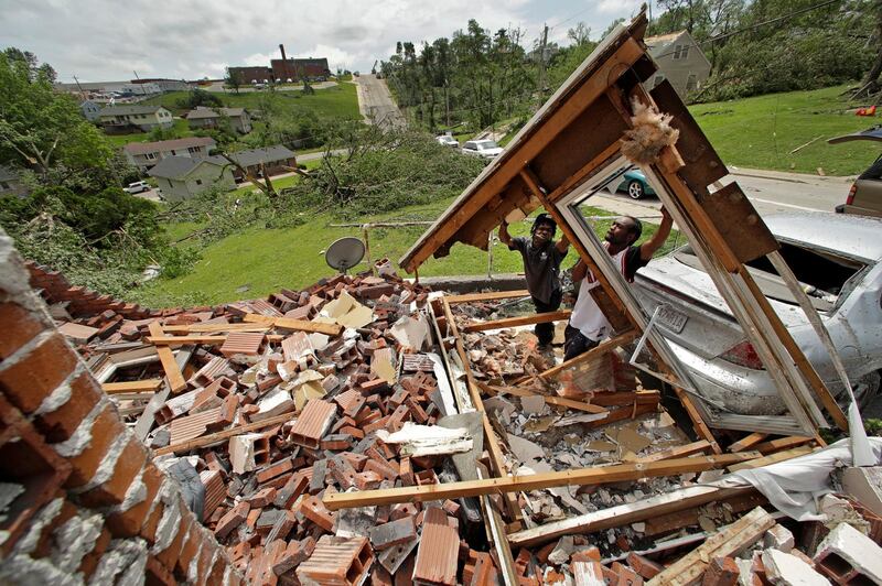 Tavaris McClain, left, and Tyree Thompson clear debris to free McClain's mother's car outside her destroyed home. AP Photo