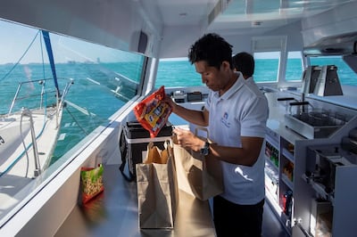 DUBAI, UNITED ARAB EMIRATES. 12 DECEMBER 2018. Trying out the new floating Carrefour mini market off the coast of Dubai. Dubai resident Marie Byrne takes her yacht out to try the new Carrefour floating shop. The floating shop has an assortment of items from icecream to fresh salads and dry goods. An employee packes an order into delivery bags. (Photo: Antonie Robertson/The National) Journalist: Nicke Webster. Section: National.
