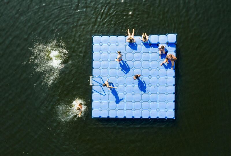 Aerial view taken shows bathers on and around a pontoon floating on the Altwarmbuechener See lake in Hanover, northern Germany,. AFP