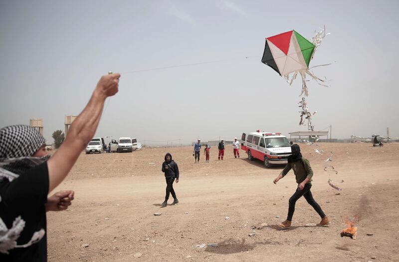 FILE - In this April 20, 2018 file photo, Palestinian protesters fly a kite with a burning rag dangling from its tail during a protest at the Gaza Strip's border with Israel. Israeli border towns are coping with incendiary kites and balloons that have not been lethal but have devastated their farmlands and nature reserves. Since March 30 near-weekly Palestinian border protests have torched some 7,000 acres (2,800 hectares) of Israeli land and caused some $2 million in damages, while Israeli forces have killed more than 120 Palestinians and wounded over 3,800. (AP Photo/Khalil Hamra, File)