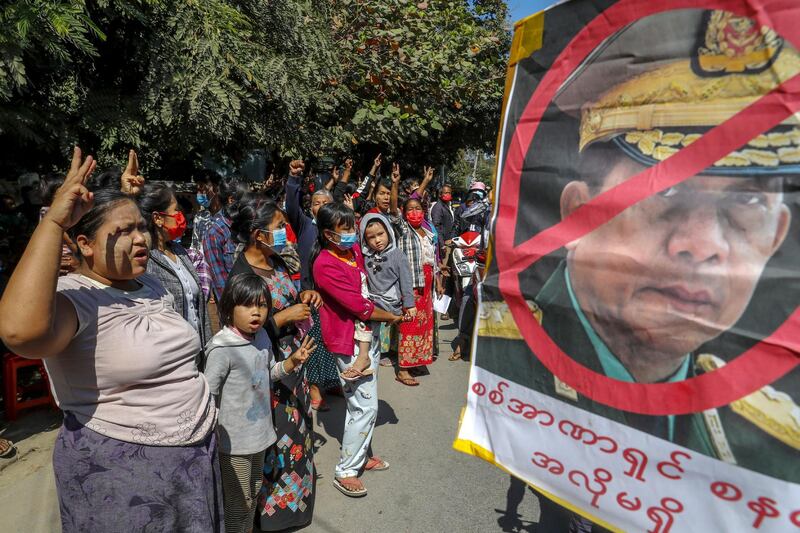 Demonstrators shout slogans and flash the three-fingered symbol of resistance against the military coup standing next to a defaced image of Myanmar military Commander-in-Chief Senior Gen. Min Aung Hlaing in Mandalay, Myanmar, Wednesday, Feb. 10, 2021. In the month since Feb. 1 coup, the mass protests occurring each day are a sharp reminder of the long and bloody struggle for democracy in a country where the military ruled directly for more than five decades. (AP Photo)