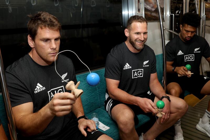 New Zealand rugby players Matt Todd, Kieran Read and Ardie Saveas play the Japanese game Kendama on a train in Kashiwanoha, Japan. Getty