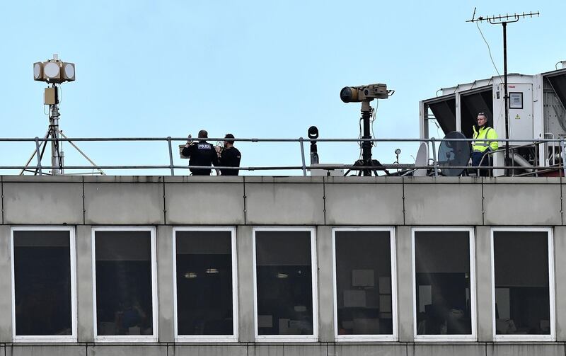 Police officers stand near equipment on the rooftop of a building. AFP