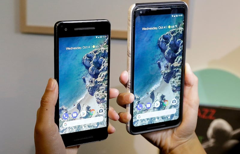 A woman holds up the Google Pixel 2 phone, left, next to the Pixel 2 XL phone at a Google event at the SFJAZZ Center in San Francisco, Wednesday, Oct. 4, 2017. (AP Photo/Jeff Chiu)