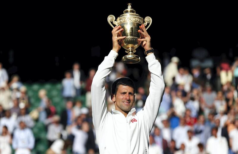 Serbia's Novak Djokovic holds the winner's trophy after beating Switzerland's Roger Federer in the men's singles final match during the presentation on day thirteen of  the 2014 Wimbledon Championships at The All England Tennis Club in Wimbledon, southwest London, on July 6, 2014. Djokovic won his second Wimbledon title and seventh career major with a 6-7 (7/9), 6-4, 7-6 (7/4), 5-7, 6-4 victory over Roger Federer Sunday, shattering the Swiss star's dream of a record eighth triumph in a titanic struggle. AFP PHOTO / POOL / TOBY MELVILLE - RESTRICTED TO EDITORIAL USE (Photo by SANG TAN / POOL / AFP)