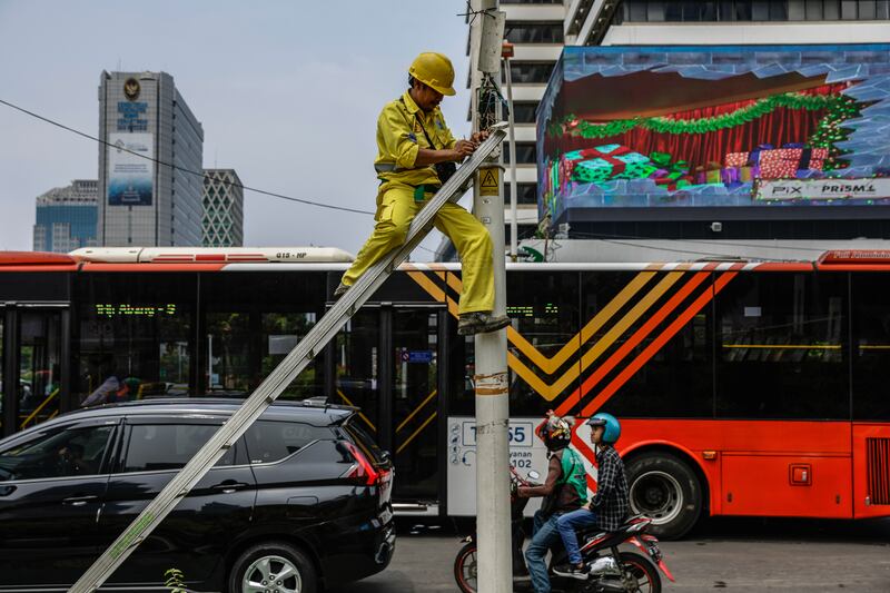 A technician works on a street light at a busy intersection in Jakarta, Indonesia. EPA