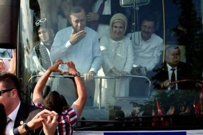 A supporter of Recep Tayyip Erdogan makes a heart shaped sign to the Turkish prime minister and his wife, Emine, after his arrival in Ankara on Sunday. Vadim Ghirda / AP Photo
