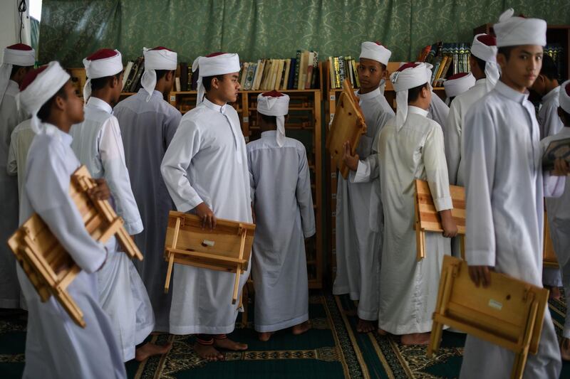 Students in Bentong, outside Kuala Lumpur carry their wooden rehals, a foldable bookrest used for placing the Quran when reading and reciting, after completing their studies. AFP