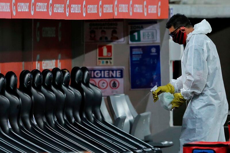 A worker sanitizes the reserve bench during the closed-door Copa Libertadores group phase football match between Brazil's Athletico Paranaense and Bolivia's Jorge Wilstermann at the Arena da Baixada stadium in Curitiba, Brazil. AFP