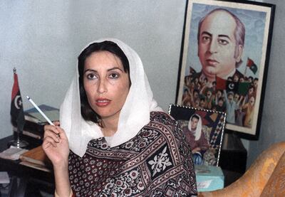 Pakistani People's Party (PPP) leader, Benazir Bhutto holds a press conference in front of a poster of her father, executed Prime minister Zulfikar Ali Bhutto, at her home, 17 November 1988 in Larkana, as she won first parliamentary elections. / AFP PHOTO / DOUGLAS E. CURRAN