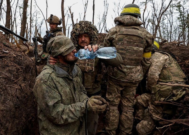A Ukrainian soldier gives water to a captured Russian army serviceman near Bakhmut, where one of the commanders died. Reuters