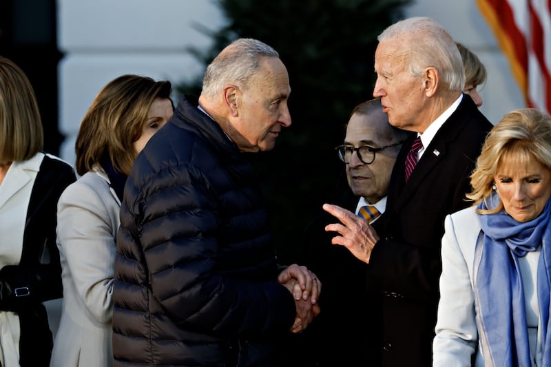 Mr Biden shakes hands with Senate Majority Leader Chuck Schumer after signing the bill. Bloomberg 