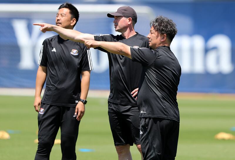 Yokohama head coach Harry Kewell, centre, passes on instructions to his fellow coaches.