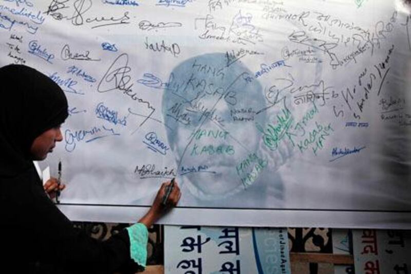 A Muslim woman signs a banner demanding the execution of convicted terrorist Ajmal Kasab, at Chhatrapati Shivaji train station in Mumbai, India, Friday, Nov. 26, 2010. India marked the second anniversary of the Mumbai terror attack Friday with somber ceremonies and a renewed promise to seek justice for the 166 people slain in an assault that has set back peace efforts with archrival Pakistan. Kasab, the only gunman to survive the assault, has been sentenced to death in India, but none of the seven alleged masterminds arrested in Pakistan has been put on trial. (AP Photo/Rajanish Kakade)