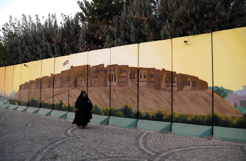 A woman walks past a mural depicting the Citadel in Arbil, Iraq. AFP