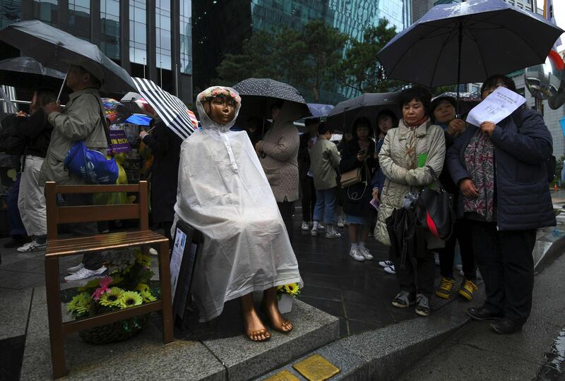 South Korean protesters stand next to a statue of a teenage girl symbolising "comfort women" in Seoul. AFP