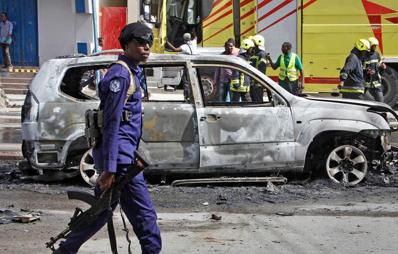 A member of security forces walks past the burned-out vehicle after a bomb planted in it exploded in Mogadishu, Somalia Tuesday, March 26, 2019. A Somali police officer says the bomb exploded killing the driver and injuring a nearby pedestrian in the Hodan district of the capital. (AP Photo/Farah Abdi Warsameh)