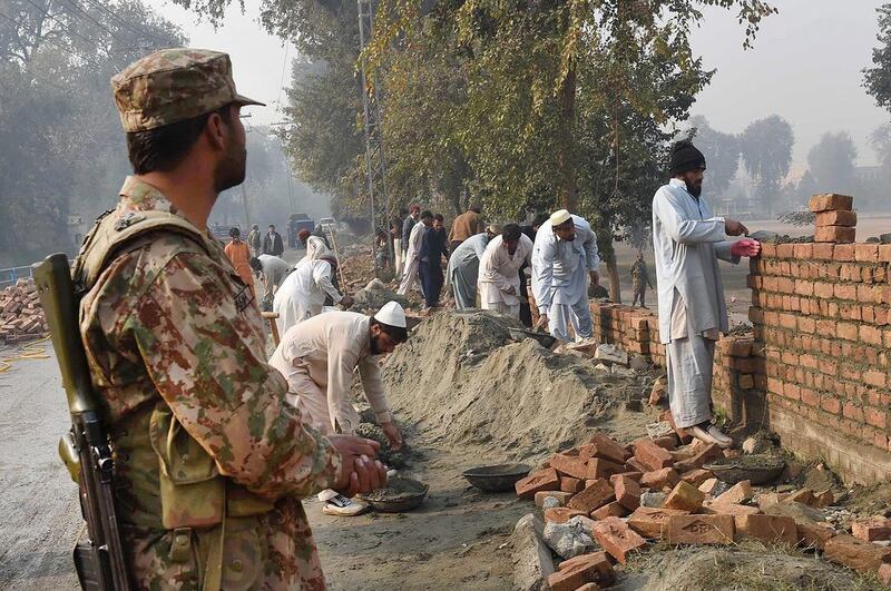 Pakistani labourers rebuild the wall of an army-run school, which was attacked by Taliban militants, in Peshawar on December 21, 2014. A Majeed/AFP Photo

