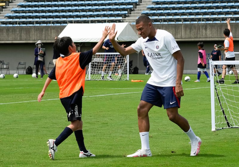 Paris Saint-Germain's Kylian Mbappe high fives a child during the PSG kids soccer clinic in Tokyo, Japan. EPA