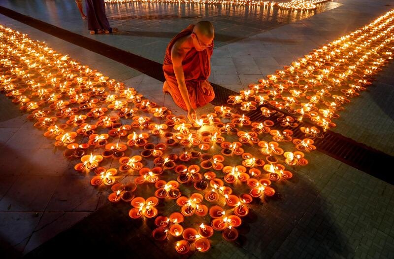 A Buddhist monk lights up an earthen lamp while worshiping at the Botataung Pagoda on the Thadinkyut full moon day in Yangon, Myanmar.  EPA