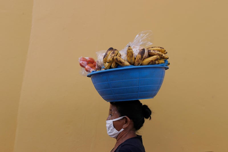 Guillerma Torres, wearing a face mask to curb the spread of the new coronavirus, carries a basket of fruit on her head to sell, on a street in Tegucigalpa, Honduras. AP Photo