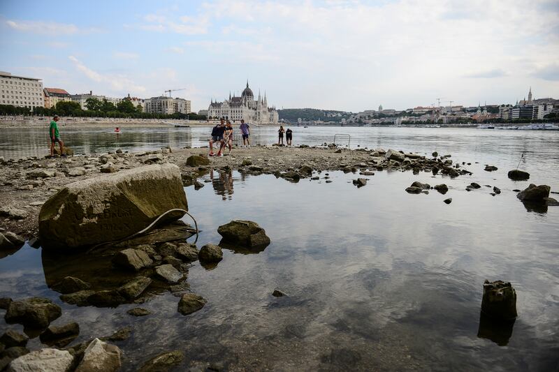 People take photos on the southern tip of Margaret Island, which can be seen due to low water level of the River Danube,  in Budapest, Hungary. AP