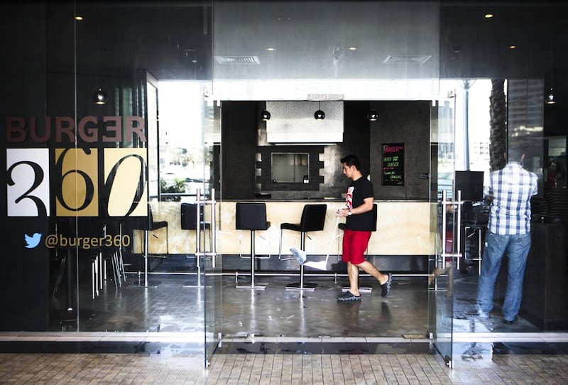 A fire at a ground floor restaurant Burger 360 forced Marina Tower in Dubai to evacuate its tenants. Seen here, walking by while cleaning the restaurant  is Avelino, an employee at the resurant. Lee Hoagland/The National



