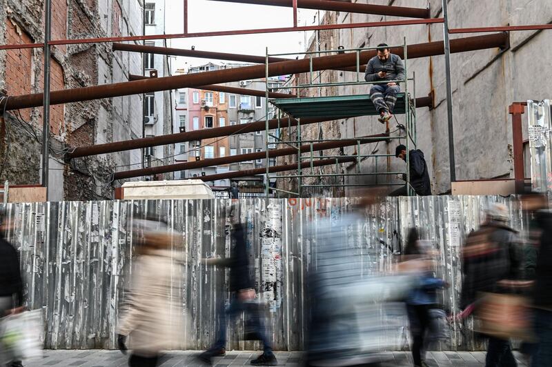 Construction workers take a break on scaffolding as people walk on Istiklal avenue at Beyoglu district, in Istanbul. AFP