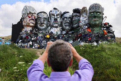 A man photographs "Mount Recyclemore", an artwork depicting the G7 leaders looking towards Carbis Bay, made from electronic waste by Joe Rush and Alex Wreckage, ahead of the G7 summit, at Hayle Towans in Cornwall, Britain, June 8, 2021. REUTERS/Tom Nicholson  REFILE – CORRECTING ARTWORK NAME AND ADDING ARTIST     TPX IMAGES OF THE DAY