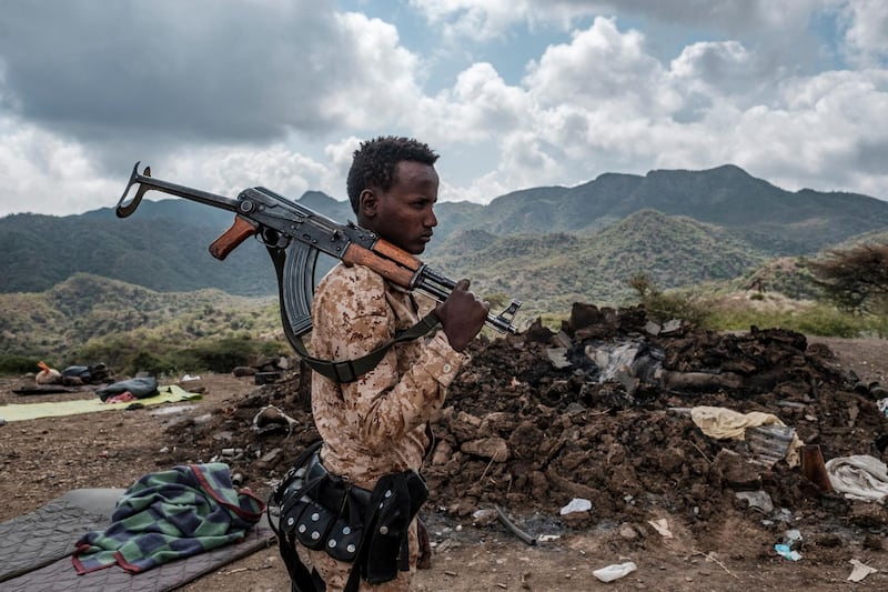 (FILES) In this file photo taken on December 09, 2020 A member of the Afar Special Forces stands in front of the debris of a house in the outskirts of the village of Bisober, Tigray Region, Ethiopia. Several houses in the village were damaged during the confrontations between the Tigray Forces and the Ethiopian Defense Forces. It has been six months since Ethiopian Prime Minister Abiy Ahmed sent troops into the country's northernmost Tigray region for a military campaign he vowed would be swift and targeted. 
However the violence rumbles on and reports continue to emerge of massacres, rape and widespread hunger. / AFP / EDUARDO SOTERAS
