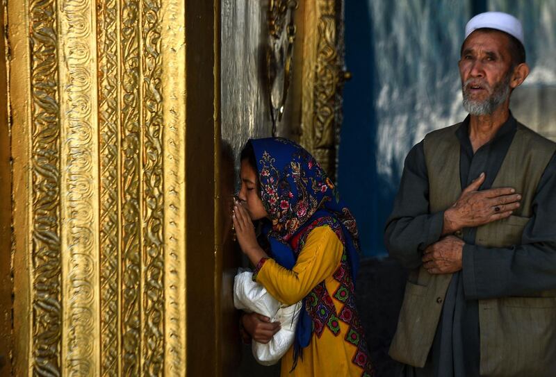 An Afghan girl kisses a doorway as she prays in the courtyard during Ramadan at the courtyard of the Hazrat-e-Ali shrine in Mazar-i-Sharif. AFP