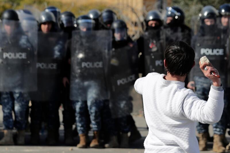 An anti-government protester holds a knife as throws stones at riot police during a scuffle near the parliament building in downtown Beirut. AP Photo