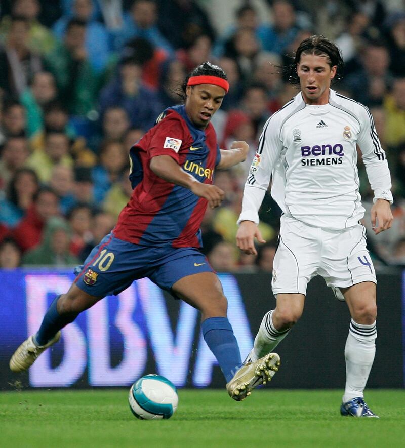 MADRID, SPAIN - OCTOBER 22: Ronaldinho (L) of Barcelona passes the ball beside Sergio Ramos of Real Madrid during the Primera Liga match between Real Madrid and Barcelona at the Santiago Bernabeu stadium on October 22, 2006 in Madrid, Spain  (Photo by Denis Doyle/Getty Images)