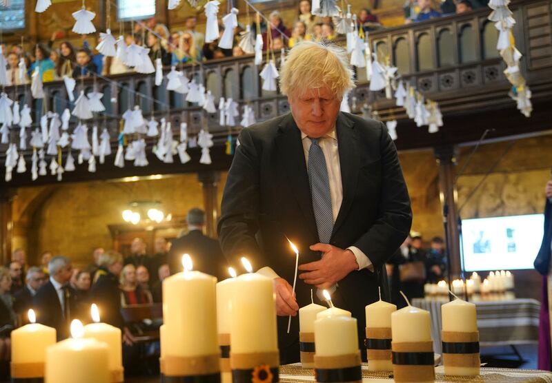 Former prime minister Boris Johnson lights one of the 52 candles – one for each week of the war – at the Ukrainian Catholic Cathedral in London. AP