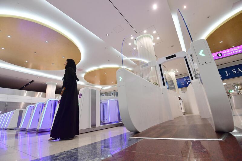 A woman stands next to a "smart tunnel " at Dubai International Airport's terminal 3 in United Arab Emirates on October 10, 2018. - The Smart tunnel using face recognition tecnology, will check the passengers passports as they walk through it. (Photo by GIUSEPPE CACACE / AFP)