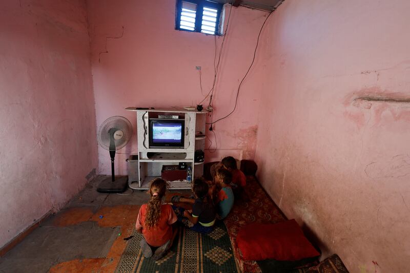 Children from the Kuhail family watch television in the family home in Sheikh Shaban cemetery. The children earn small amounts bringing water to funeral ceremonies.