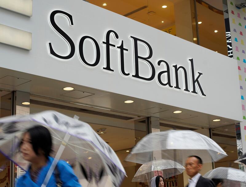 In this June 15, 2018, photo, people walk under the logo of Japanese internet company SoftBank Corp. at its mobile phone shop in Tokyo. SoftBank is investing about $2 billion to raise its stake in Yahoo Japan through an acquisition from U.S. investment company Altaba Inc., announced on Tuesday, July 10, 2018 in a statement. (AP Photo/Shuji Kajiyama)