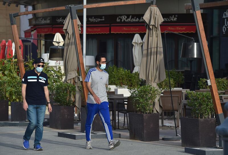 Pedestrians wearing masks to protect against Covid-19 walk past a closed restaurant in Saudi Arabia's capital Riyadh. AFP