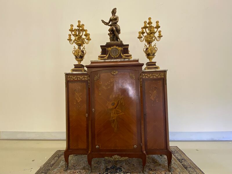 A piece of furniture decorated with a statue of a woman, candlesticks and a clock. Nada El Sawy / The National