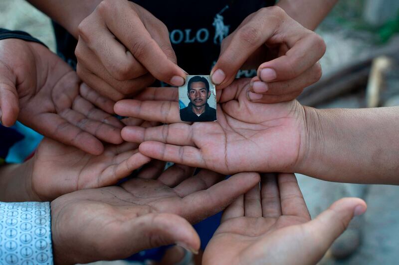 Salvadoran Rebeca Valle de Barrera, right, and her five children show a picture of her deceased husband Joaquin Barrera who, along with her parents and two other brothers, recently died of Covid-19, at their home in Santiago Nonualco, La Paz department, El Salvador. AFP