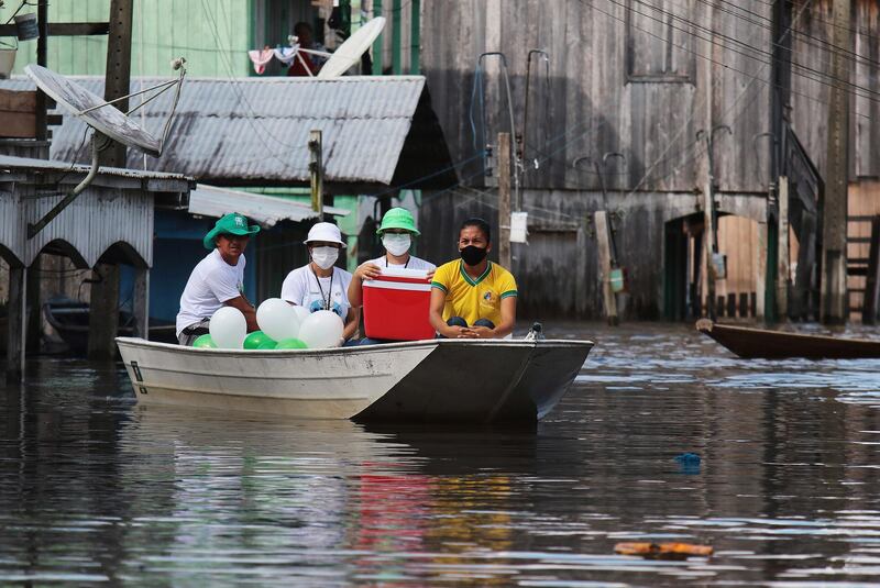 Healthcare workers navigate flooded streets to reach residents in order to vaccinate with the Sinovac COVID-19 vaccine, in Anama, Amazonas state, Brazil. AP Photo