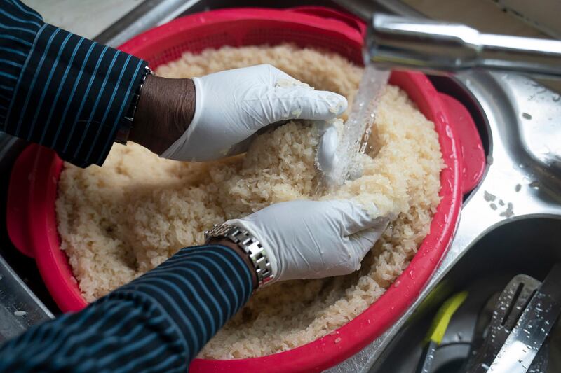 Volunteer Dave Williams washes rice as members of the Preston Windrush Covid Response team prepare meals.  AP Photo