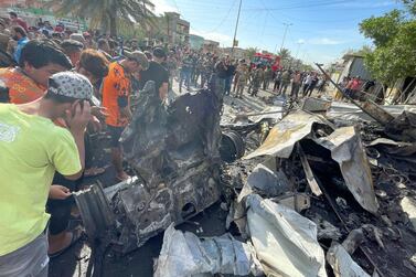 Bystanders view the wreckage after what police said was a car bomb explosion in the Sadr City district of Baghdad, Iraq on April 15, 2021. Haider Husseini / The National