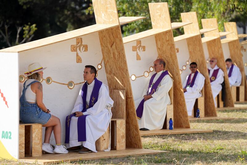 Priests listen to the confessions of pilgrims at events held for World Youth Day at a park in Lisbon. AP