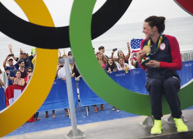 Spectators cheer for the United States’ Gwen Jorgensen as she poses with the gold medal in front of the Olympic rings after winning the women’s triathlon event on Copacabana beach at the 2016 Summer Olympics in Rio de Janeiro, Brazil, Saturday, August 20, 2016. David Goldman / AP Photo