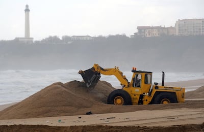 A digger builds a sand barrier on March 4, 2014 to protect the buildings close to the "Grande Plage" (Grand Beach) in Biarritz, western France, from huge waves. The French weather forecasters have issued an orange alert in the Pyrenees-Atlantiques on March 4.     AFP PHOTO / GAIZKA IROZ (Photo by GAIZKA IROZ / AFP)