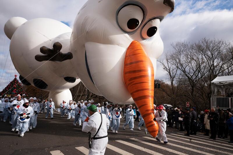 A balloon handler holds the Olaf balloon by the nose as strong winds keep Macy's Thanksgiving Day Parade balloons low to the ground  in New York. AP