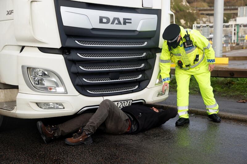 A person lies down in front of a lorry to stop it from leaving the Port of Dover, as EU countries impose a travel ban from the UK following the coronavirus disease (COVID-19) outbreak, in Dover, Britain, December 23, 2020. REUTERS/John Sibley