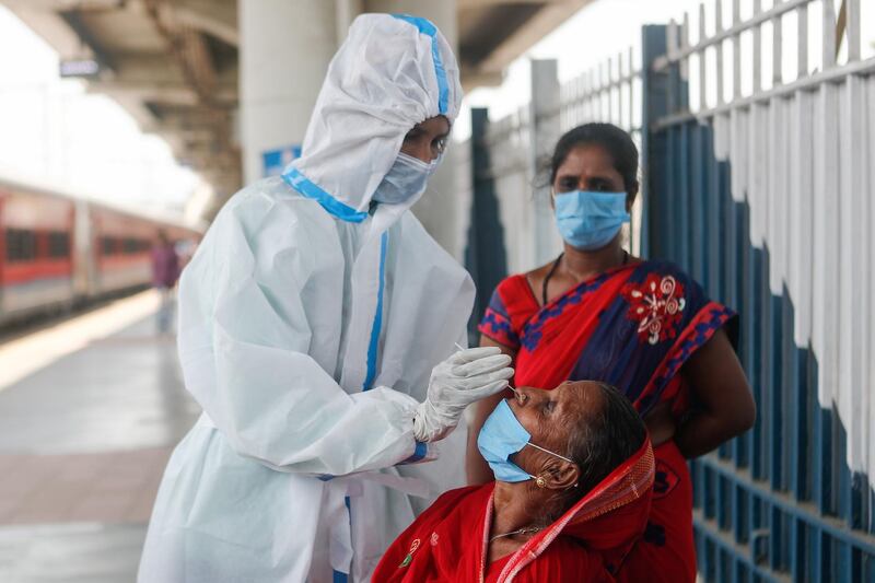 A healthcare worker in personal protective equipment (PPE) collects a swab sample from a woman, amidst the spread of the coronavirus disease (COVID-19), at a railway station in Mumbai, India, April 16, 2021. REUTERS/Francis Mascarenhas