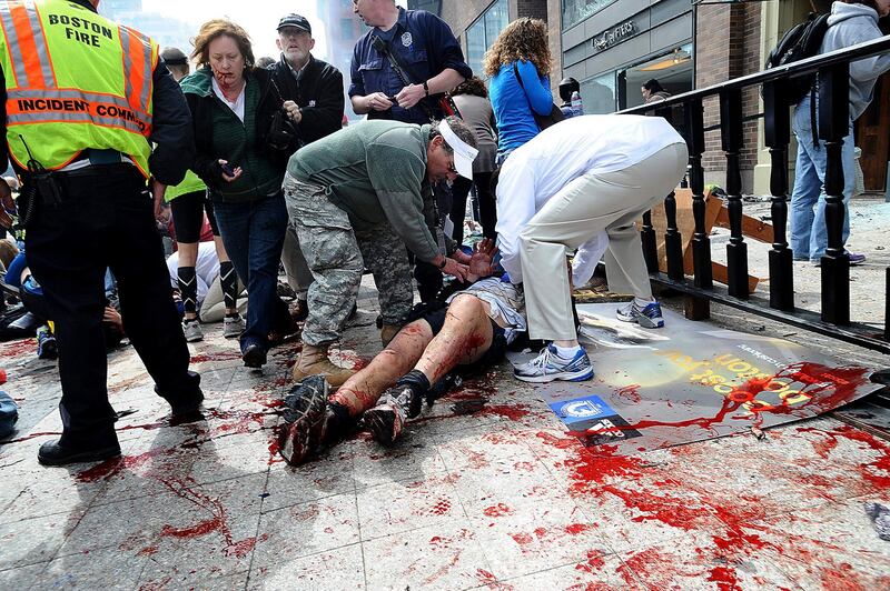 An injured person is helped on the sidewalk near the Boston Marathon finish line following an explosion in Boston, Monday, April 15, 2013. (AP Photo/MetroWest Daily News, Ken McGagh)  MANDATORY CREDIT *** Local Caption ***  Boston Marathon Explosions.JPEG-058d5.jpg